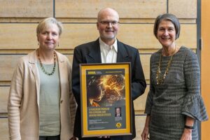 Dr. Diane Rohlman and Dr. Edith Parker honor Dr. Hans-Joachim Lehmler with a framed copy of the poster for his Distinguished Faculty Lecture on PCBs for the UI College of Public Health.